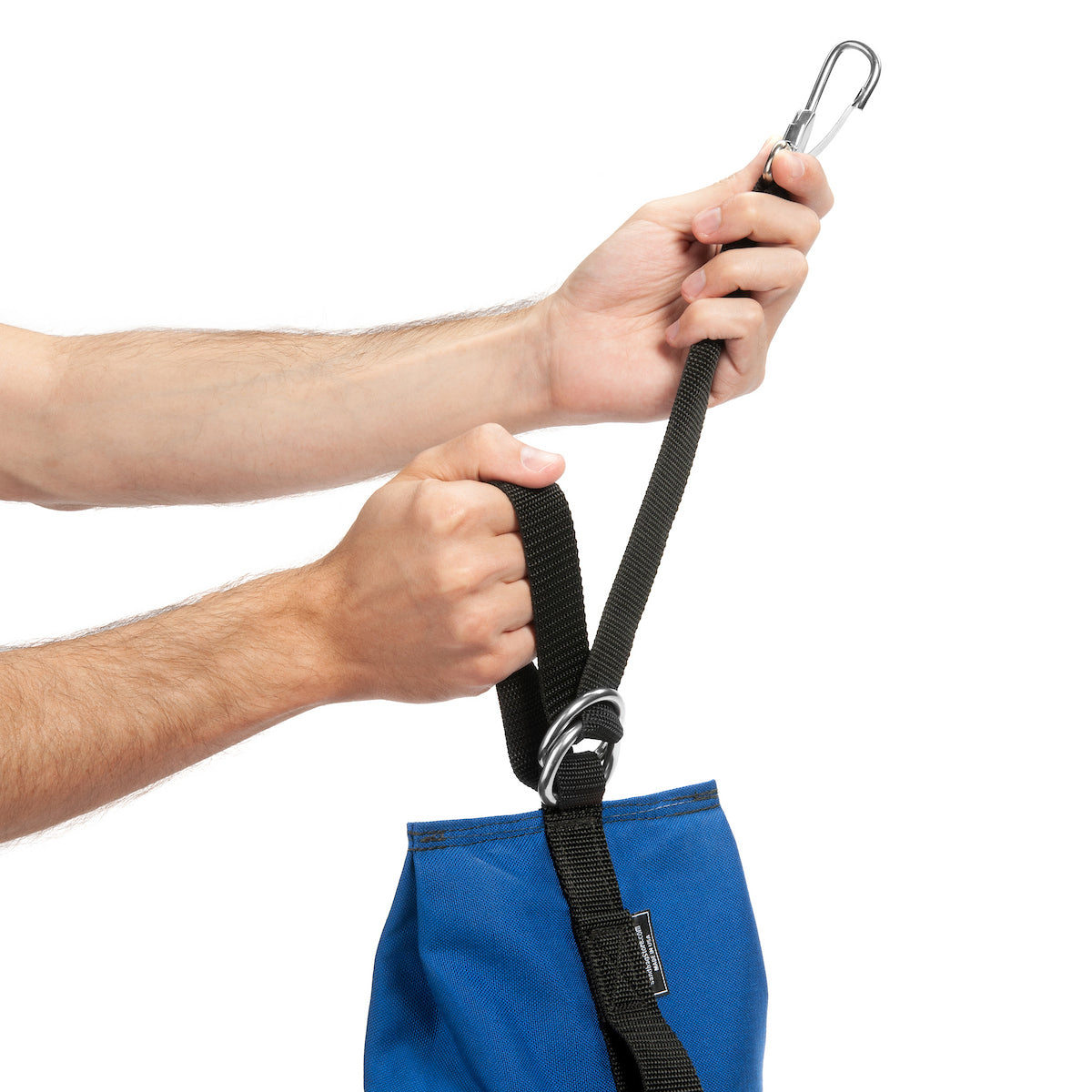 Person holding a black strap with carabiners over a blue bag on a white background