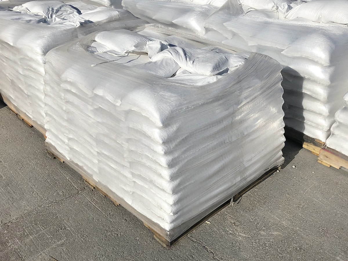 Pallets of filled white filled sandbags shrink wrapped in plastic on wooden pallets ready for shipment
