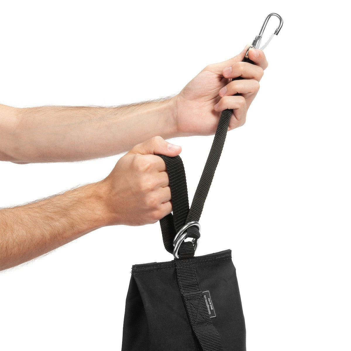 Black dropweight sandbag being held with handing strap extended on white background